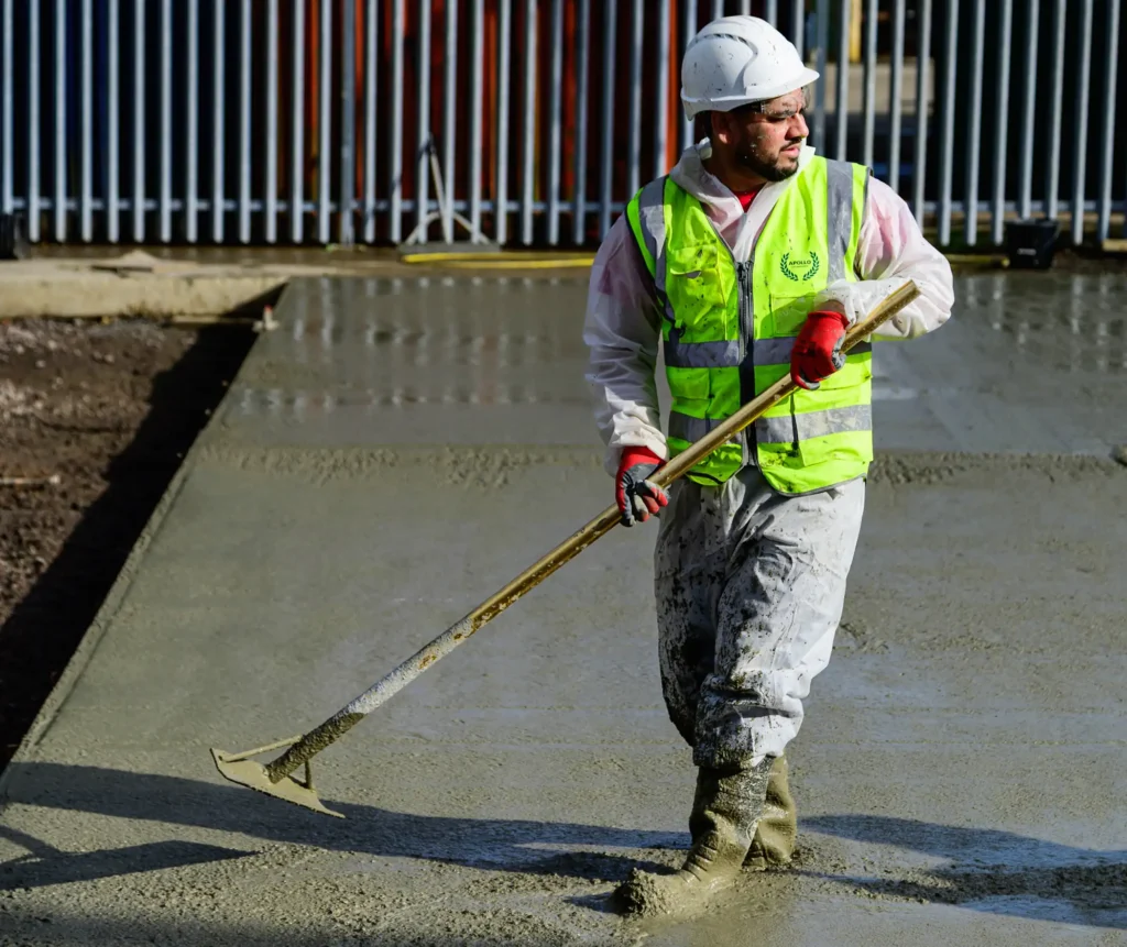 Construction Worker Leveling Fresh Concrete for Industrial Floor Installation